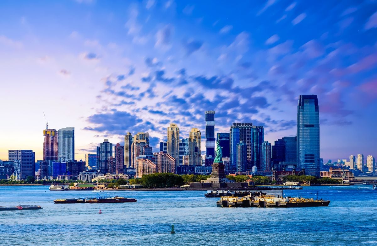 The skyline of Jersey City, New Jersey from New York Harbor with the Statue of Liberty in the foreground.