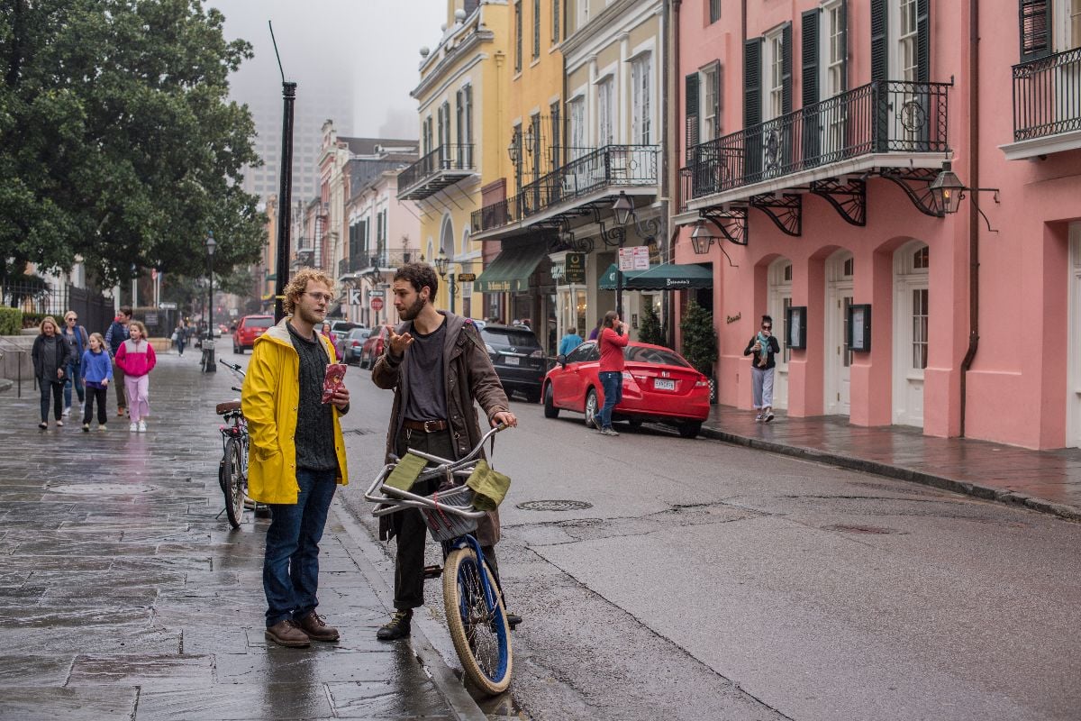 Two friends hang out and talk on the sidewalk on a rainy, winter day.
