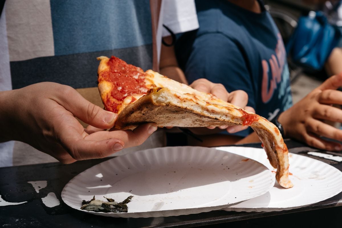 Close-up view of hand holding pizza.