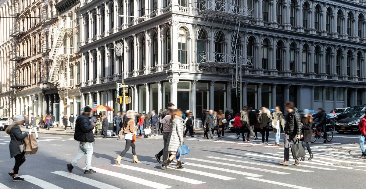 Crowds of people at the busy intersection of Broadway and Broome Street.