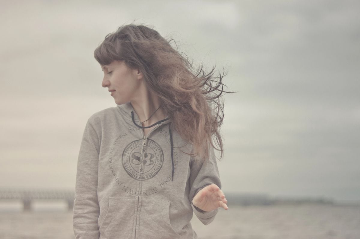 Woman in hoodie at the beach.