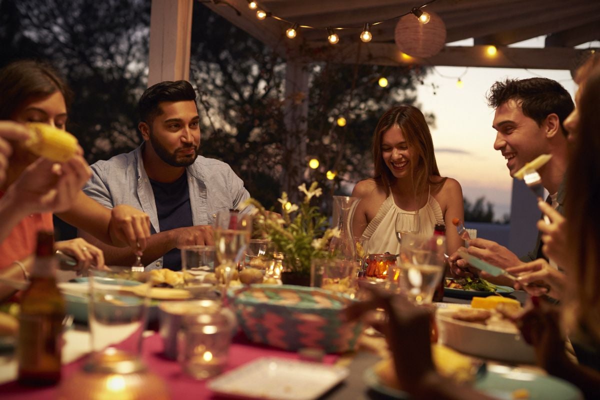 Friends eat and talk at a dinner party on a patio.