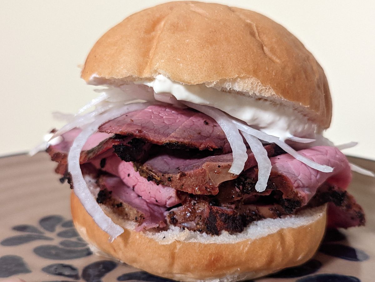 A pit beef sandwich with tiger sauce and onions.