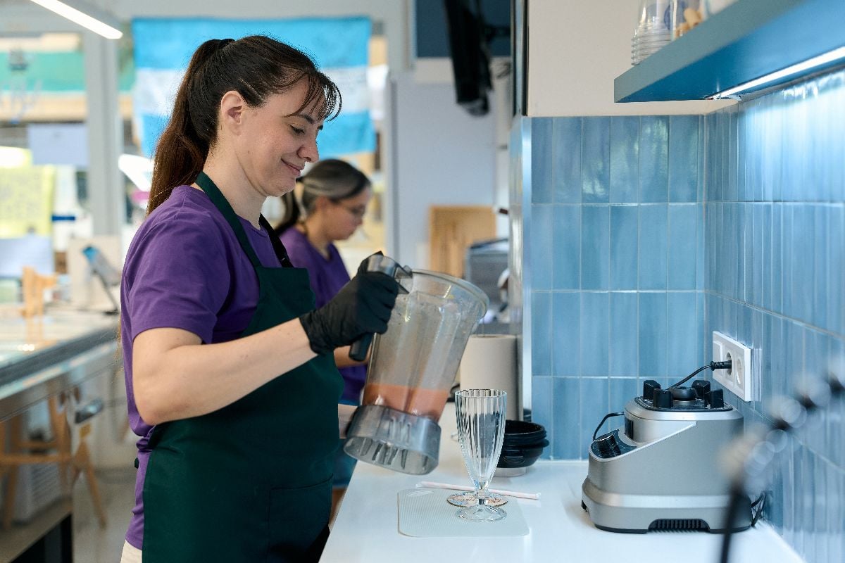 Female employee pouring a vibrant smoothie into a glass.