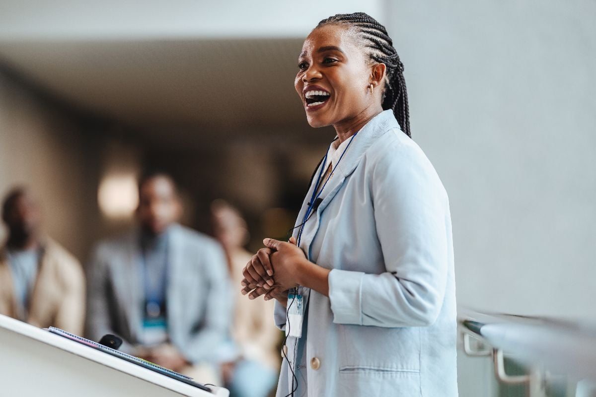 Professional woman engages attendees as she speaks at a business conference.