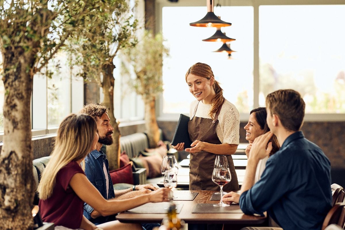 Friends enjoy a fine dining restaurant experience with attentive service and conversation.