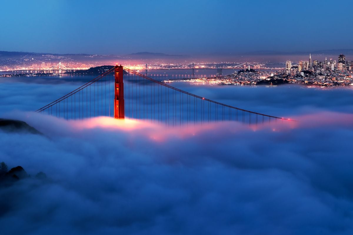 Golden Gate at night surrounded by fog.