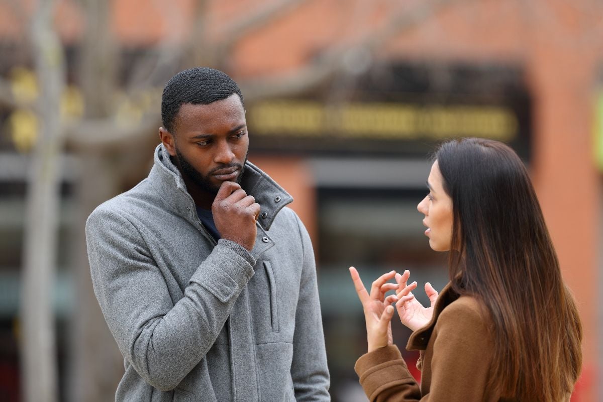 Suspicious man listening a woman talking on the street.