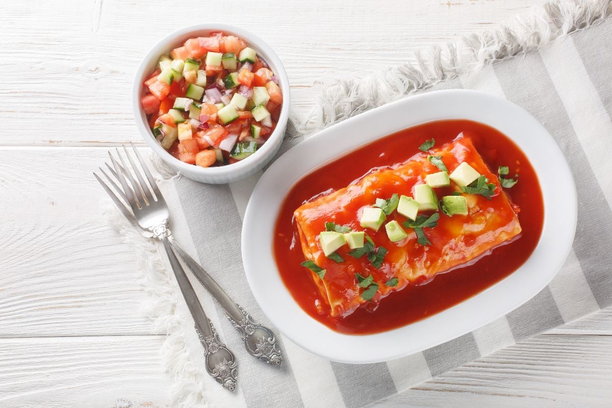 Wet burritos with a beef, rice and refried bean filling wrapped in a tortilla smothered with red sauce.
