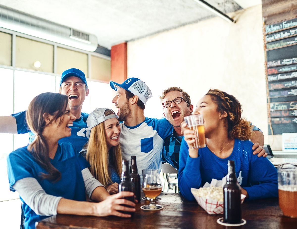 Sports fans in pub with beer and snacks.