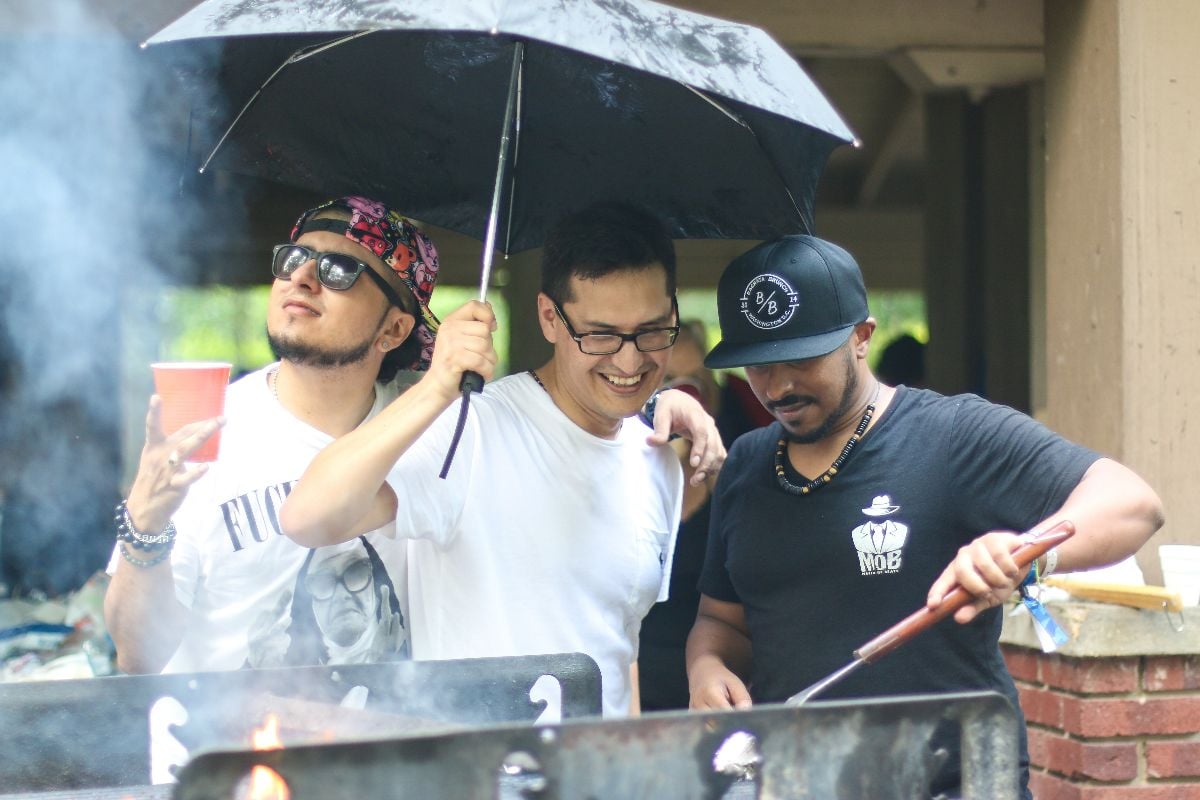 A group of young men grill meat on a rainy afternoon in a public space at Bon Air Park.