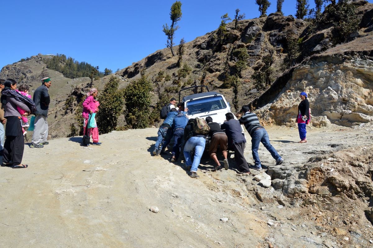 Men pushing a stranded tourist vehicle.