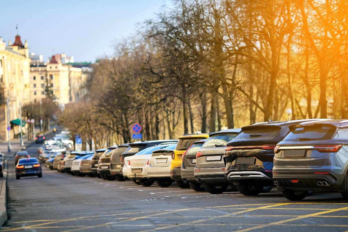 Cars parked in angled row formation in crowded city parking lot.