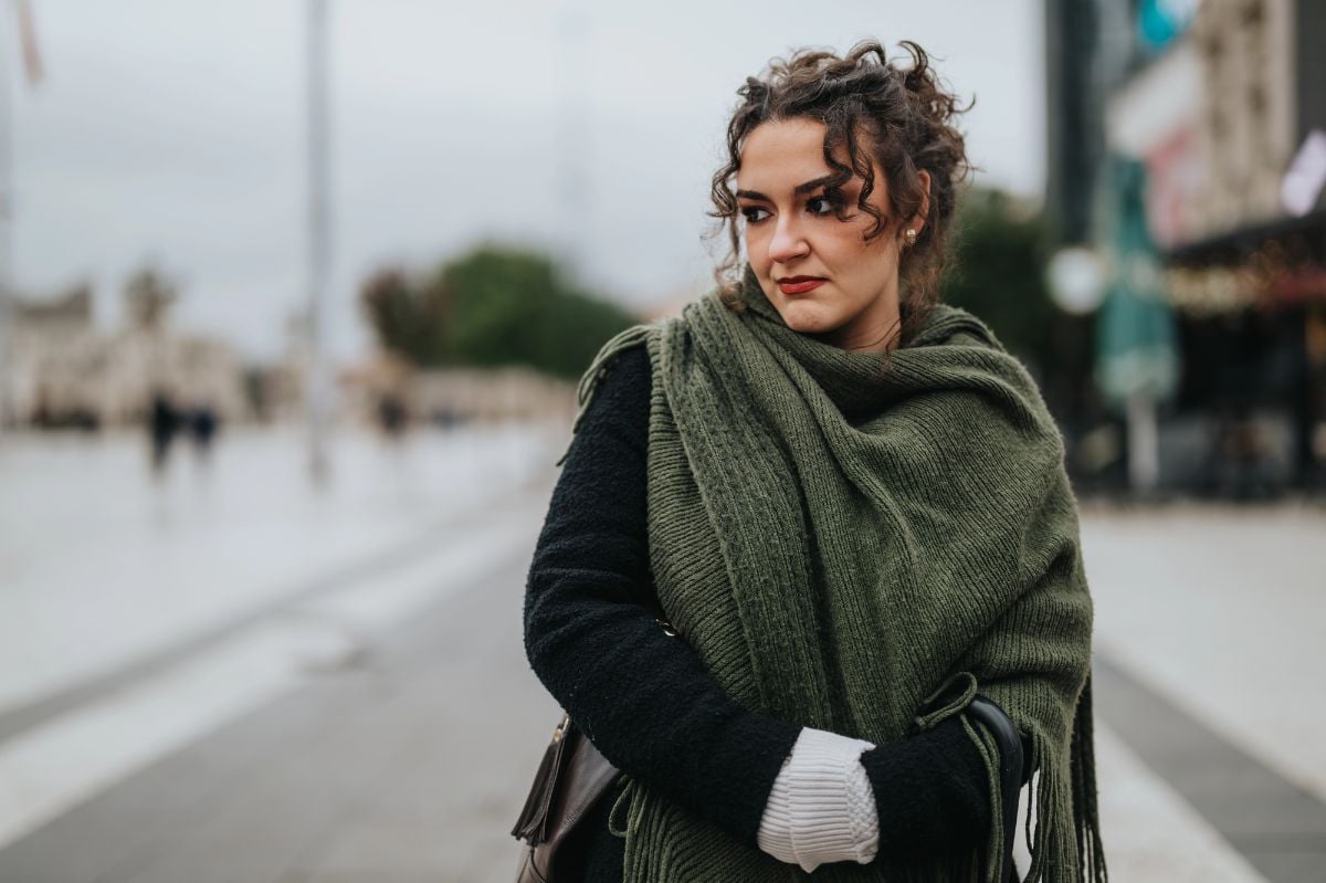 A young woman dressed in a green shawl and black sweater.
