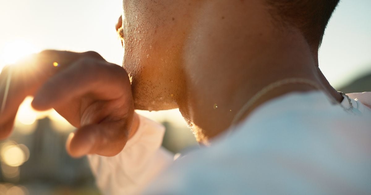 Man with sweating chin outdoors.