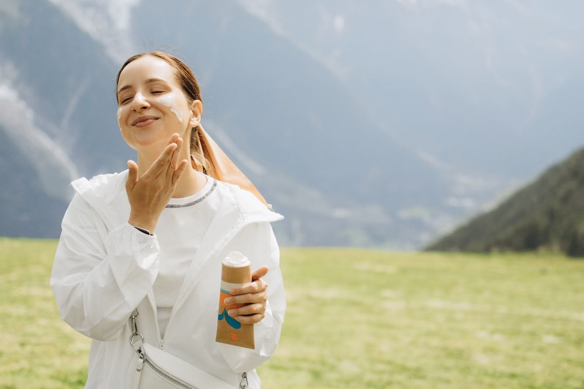 Woman applying sunscreen to her face.