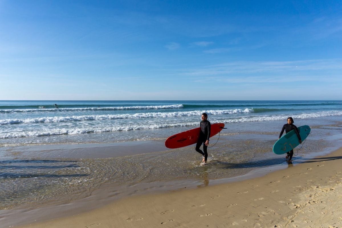 Surfers walk down the beach after a surf session.