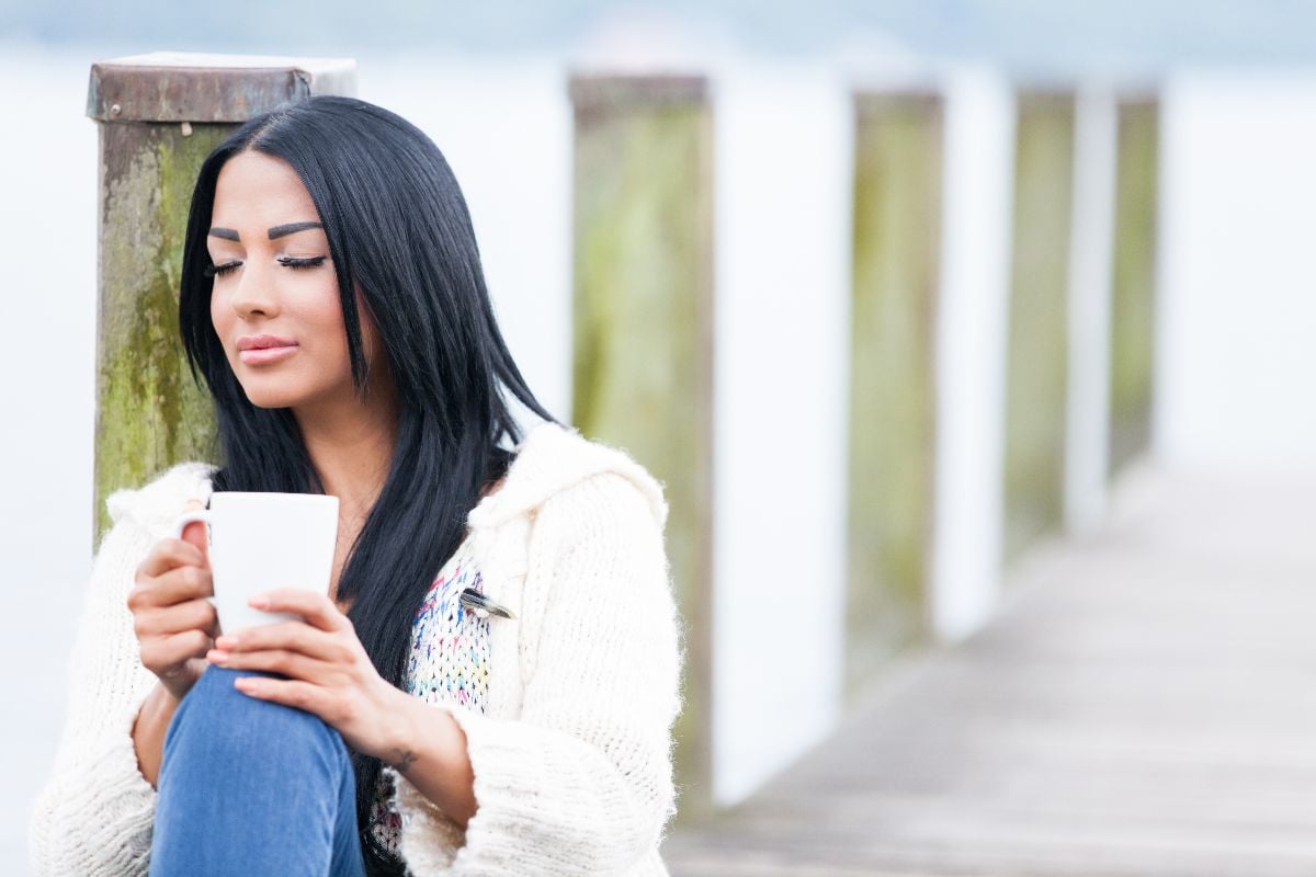 Woman in sweater on boardwalk.