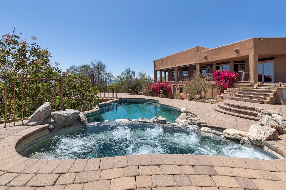 Swimming pool with hot tub and terraced patio at a luxury home.