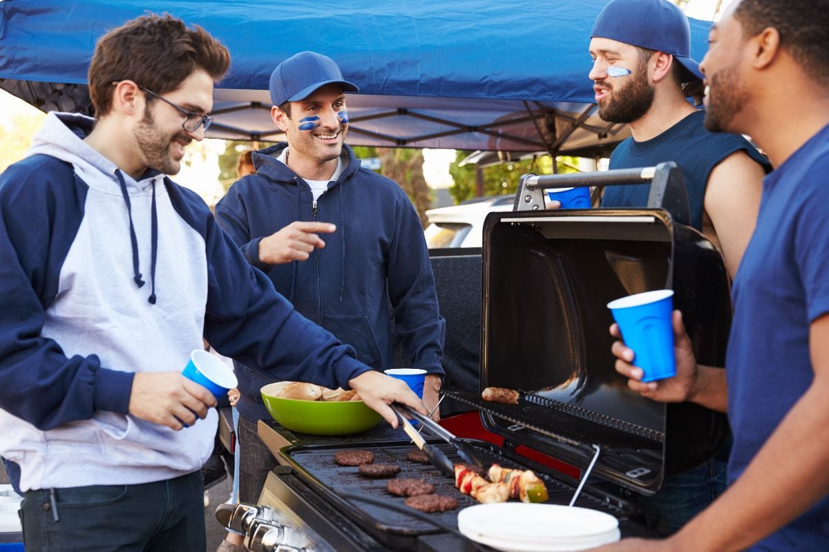 Group of sports fans tailgating in stadium car park.