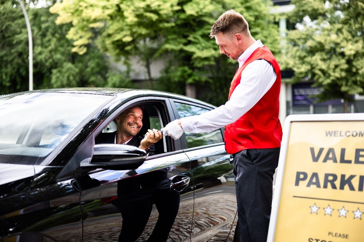 A man giving his car keys to a valet for parking.