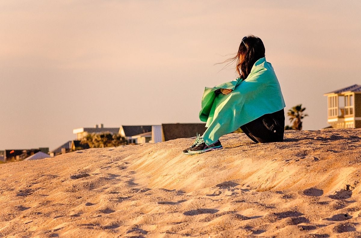 Woman sitting on the beach at sunrise.