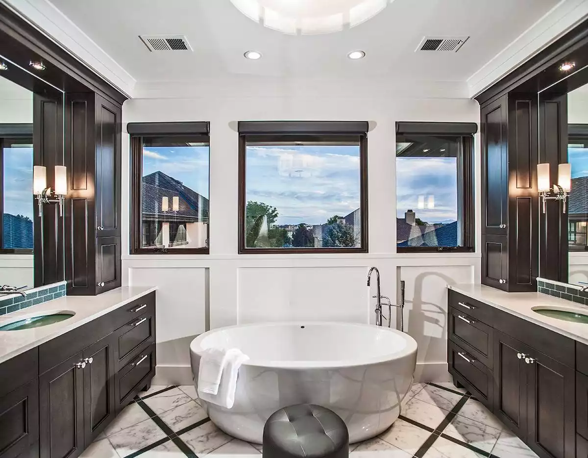 Freestanding Soaking Tub Centered Between Triple Windows and Dual Vanities