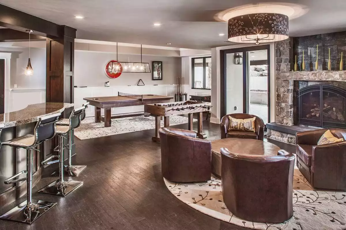 Recreation Room with Stone Fireplace, Game Tables, and Brown Leather Seating
