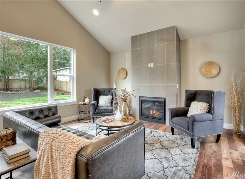 Vaulted Living Room with Gray Tiled Fireplace and Tufted Leather Seating