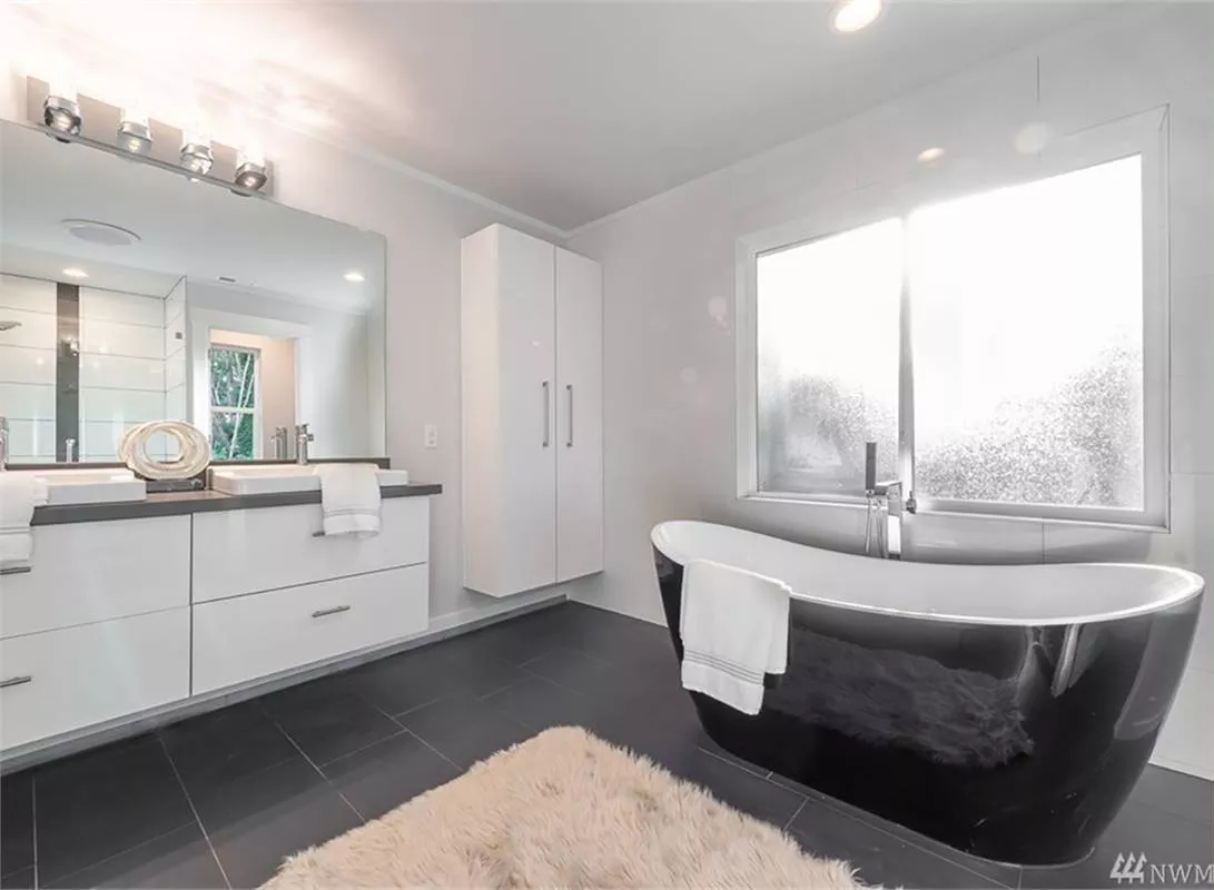 Black Chrome Tub Reflects Light While White Walls Keep the Space From Feeling Heavy