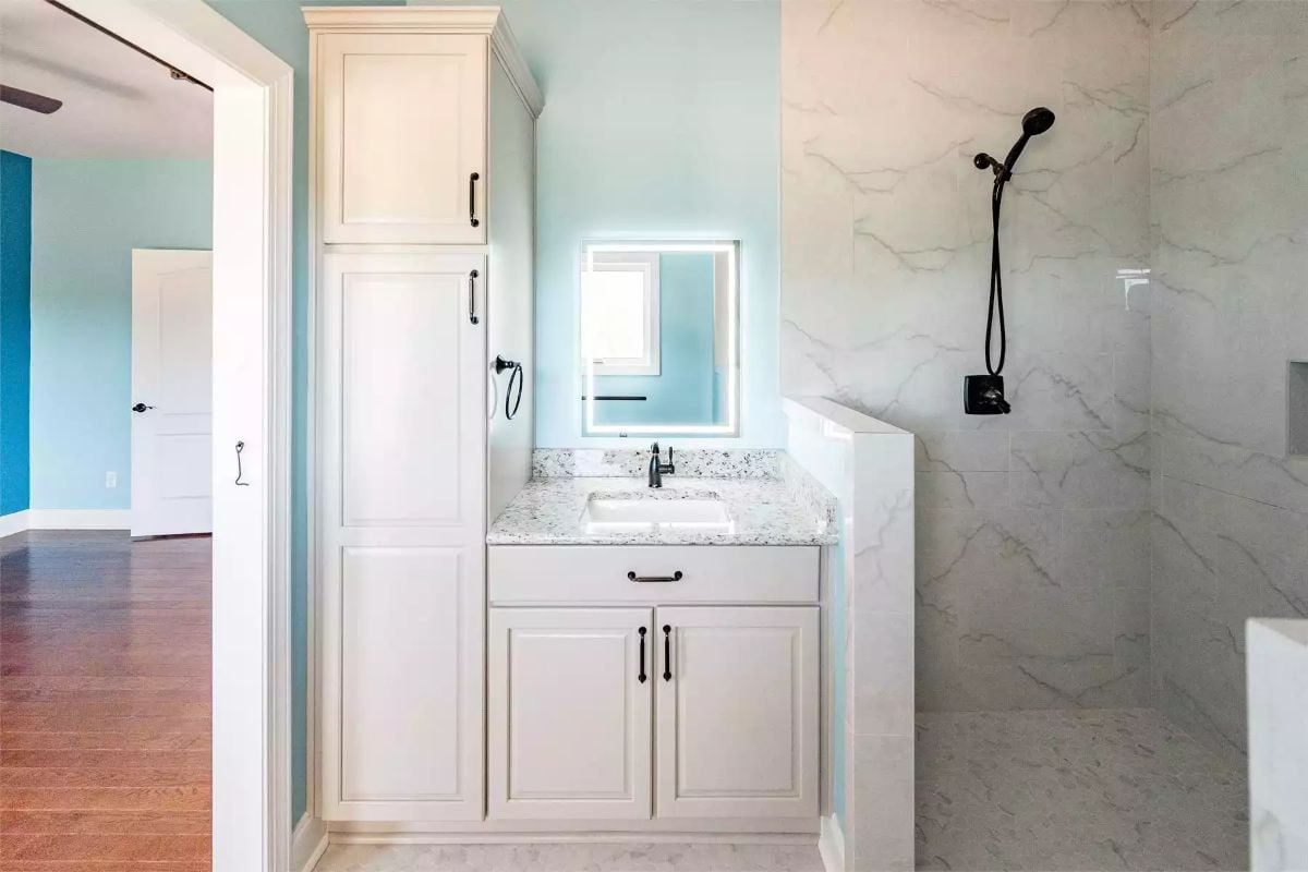 White Vanity and Marble Shower Tiles Define a Clean Bathroom