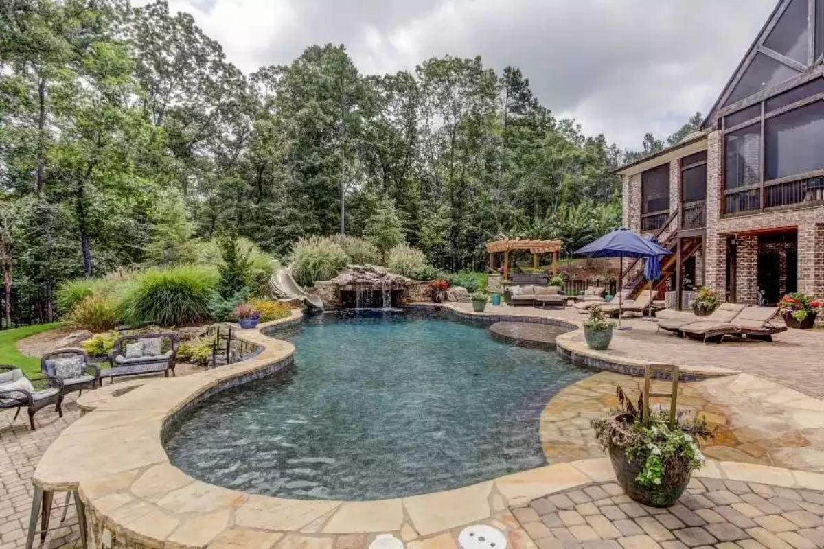 Natural Stone Waterfall Spills into Freeform Pool with Sun Shelf and Slide