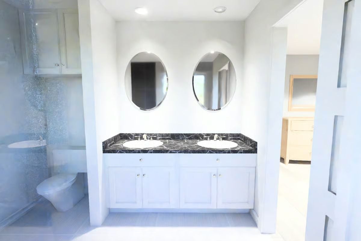 Oval Mirrors and Dark Marble Give This Double Vanity Bathroom Its Character