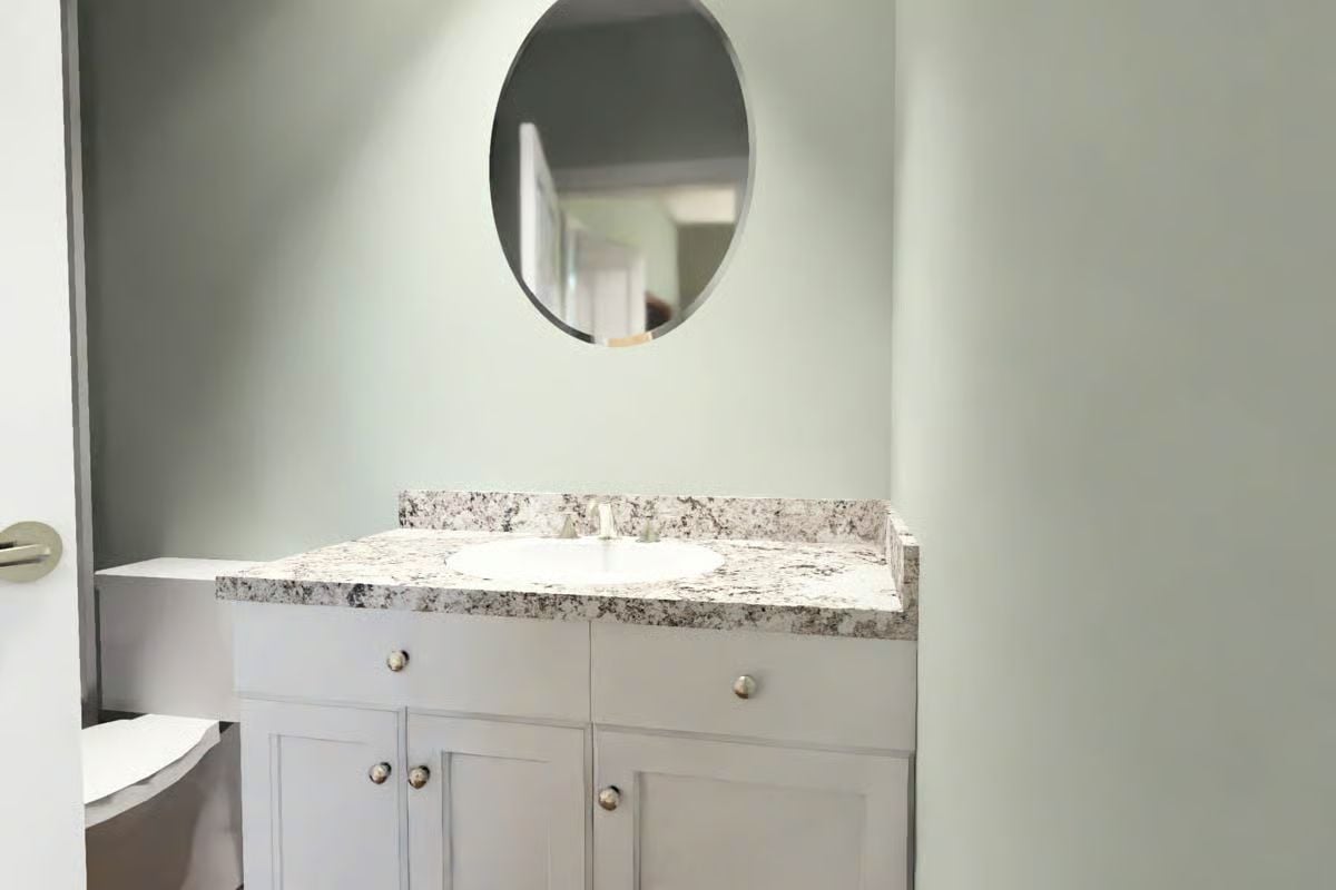 Granite Vanity Top and Round Mirror Define a Powder Room Worth Noticing