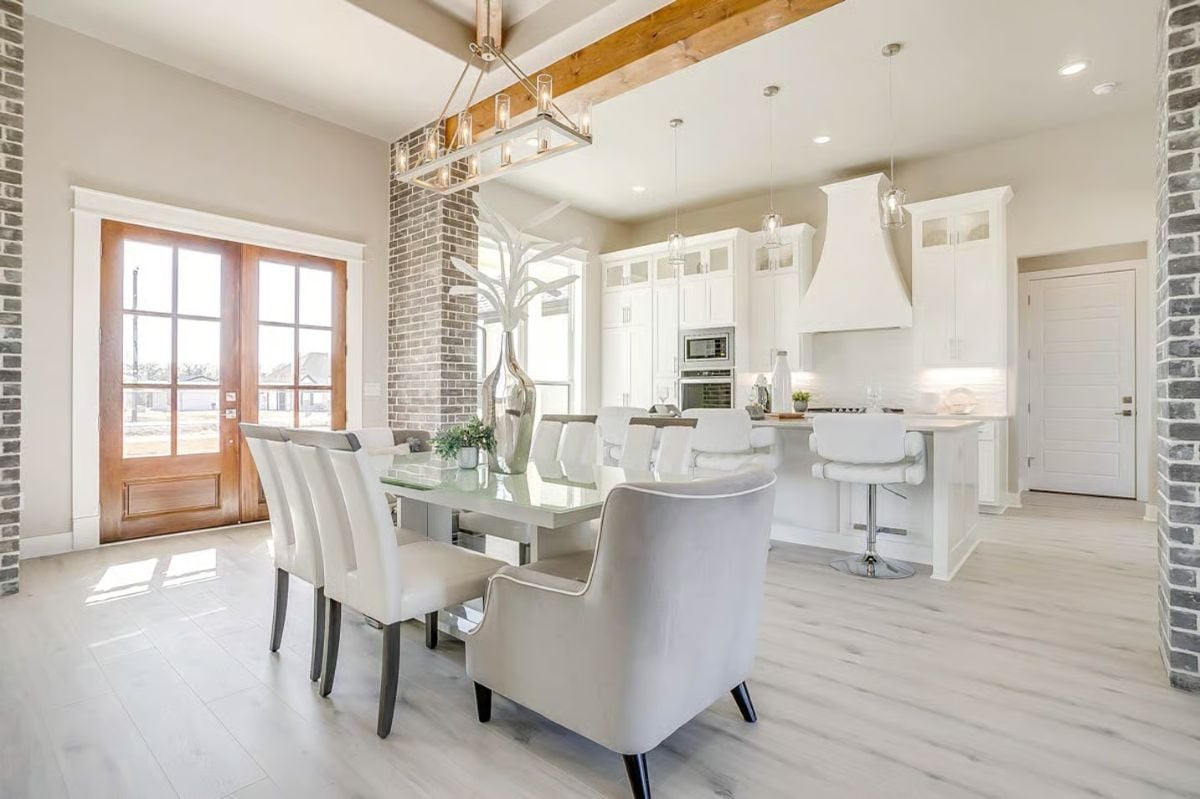 Dining Area Flowing Into Kitchen with Exposed Beam and Brick Column