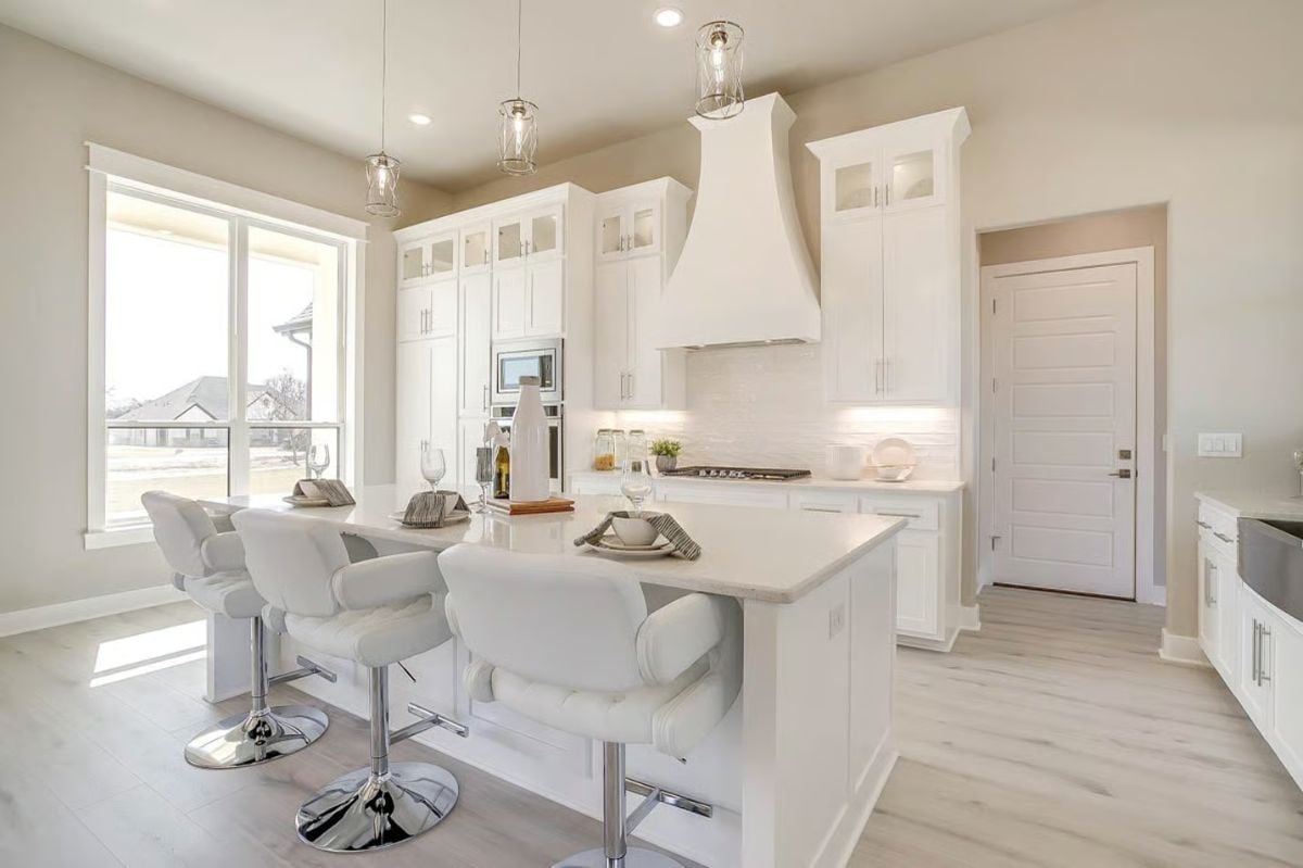 Kitchen Island with White Swivel Bar Stools and Glass Pendant Lights