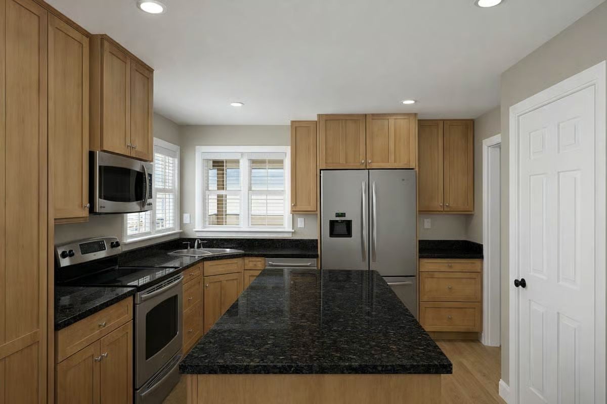 Kitchen with Natural Oak Cabinetry and Dark Granite Countertops