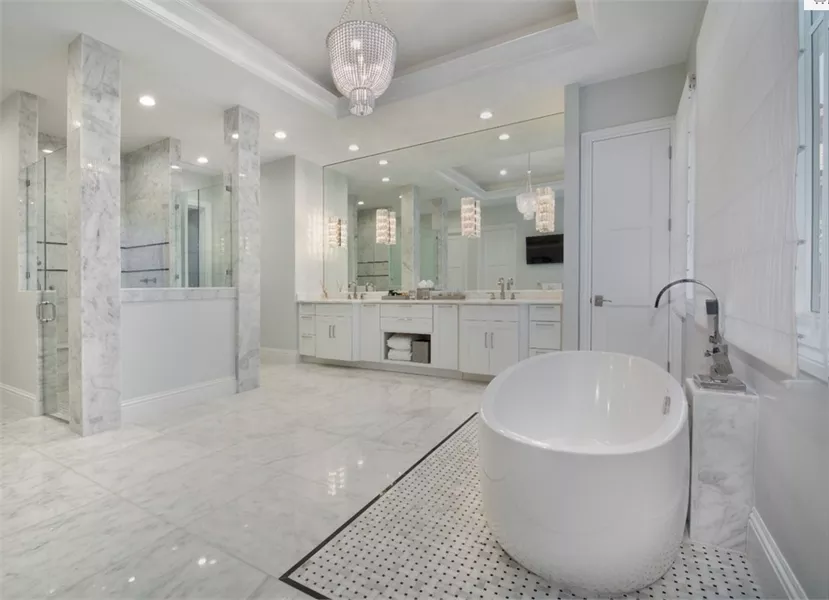 Freestanding Soaking Tub and Crystal Chandelier Command This Marble Primary Bath