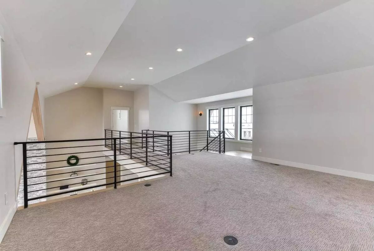 Carpeted Loft Overlooks the Main Floor Through Black Steel Railings
