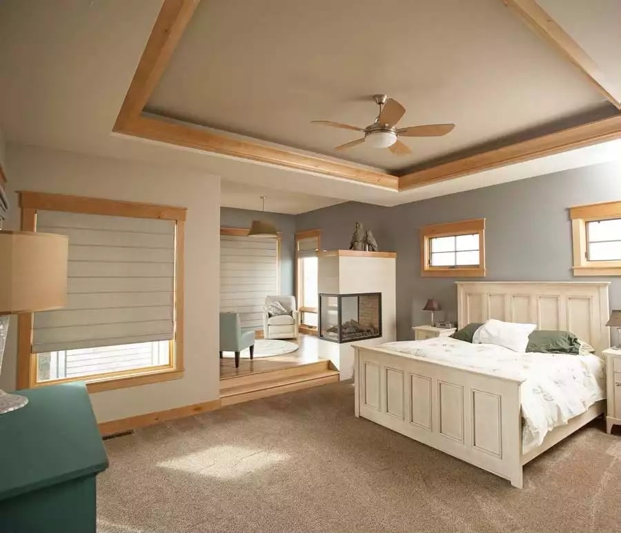 Tray Ceiling with Wood Trim Frames a Master Suite Built Around the Fireplace