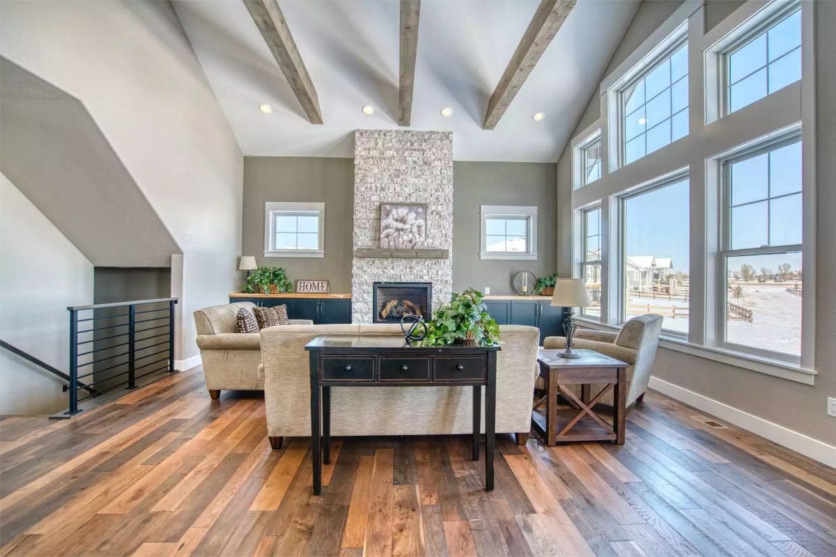 Exposed Ceiling Beams and Stone Fireplace Anchor a Farmhouse Living Room