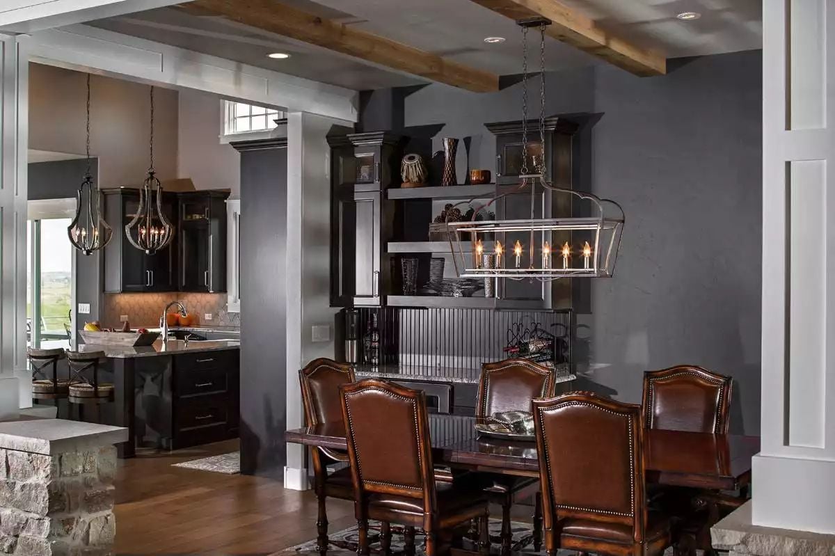 Dark Cabinets, Leather Chairs, and Exposed Beams Pull Two Rooms Into One