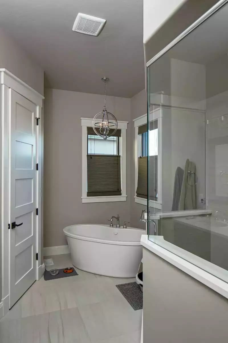 Freestanding Soaking Tub Anchored by an Orb Chandelier and Two Windows