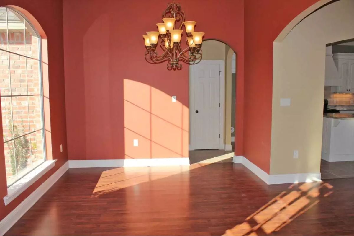 Warm Terracotta Walls and Cherry Hardwood Floors Fill an Empty Dining Room