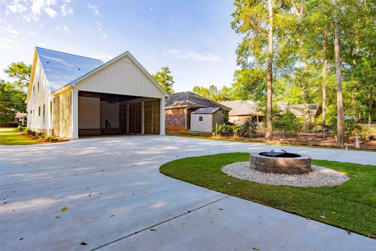 Concrete Driveway Curves Past a Fire Pit and Open Carport Bay