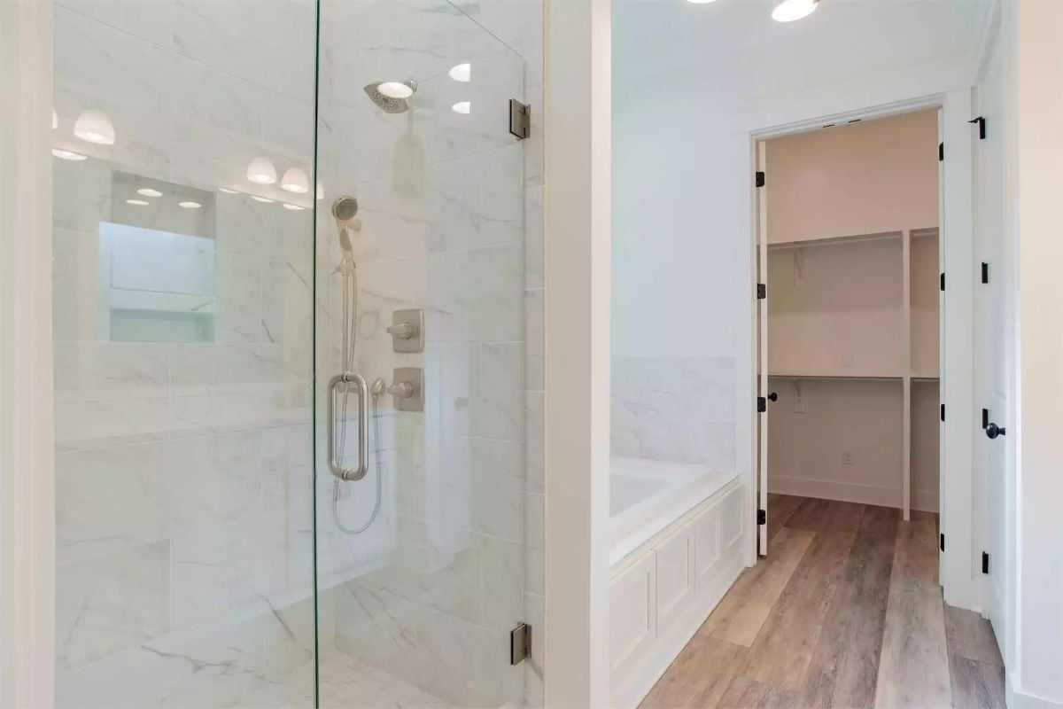 Marble Tile and Glass Enclose a Walk-In Shower Beside a Soaking Tub Alcove