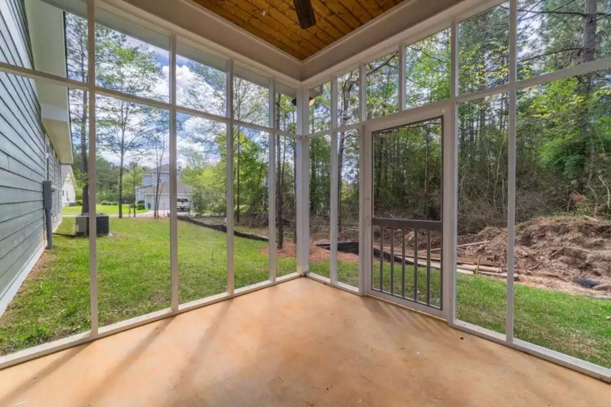 Screened Porch Opens to Wooded Backyard with Ceiling Fan Overhead