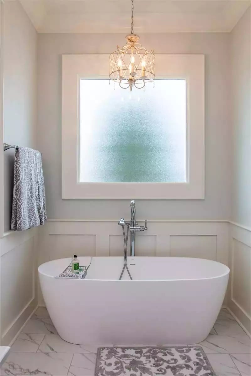 Frosted Glass, Wainscoting, and a Chandelier Make This Soaking Tub Alcove Feel Private