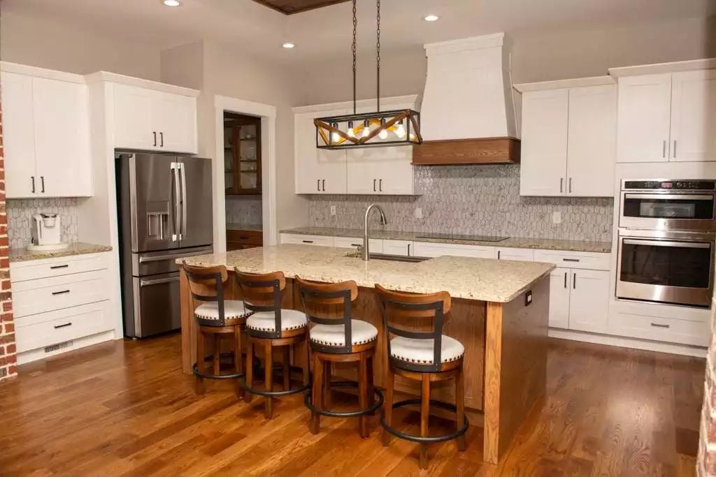 White Cabinetry and Granite Countertops Ground This Farmhouse Kitchen Island