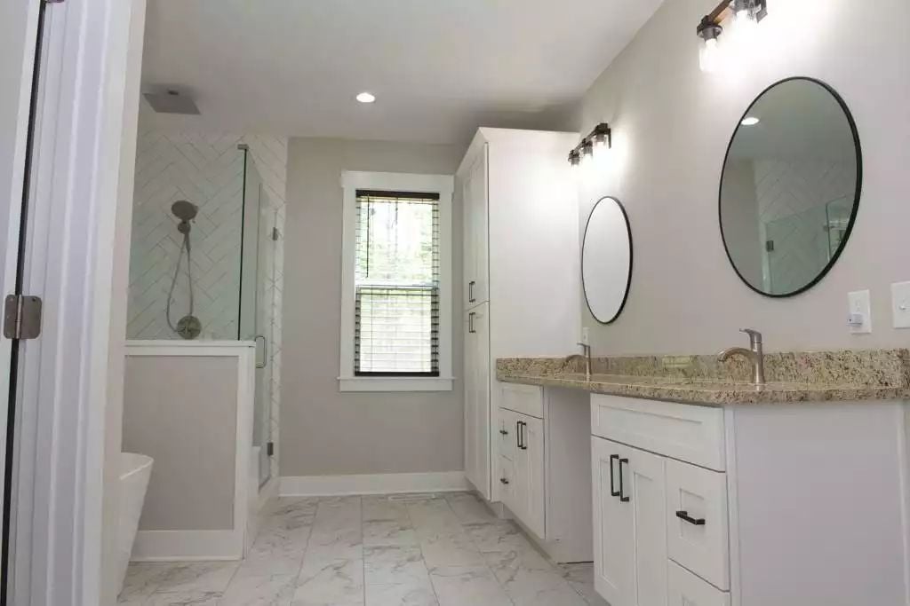 Marble Floors and Round Mirrors Bring Balance to This Farmhouse Master Bath